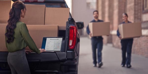 People trying to load boxes in the trunk of a GM fleet vehicle.