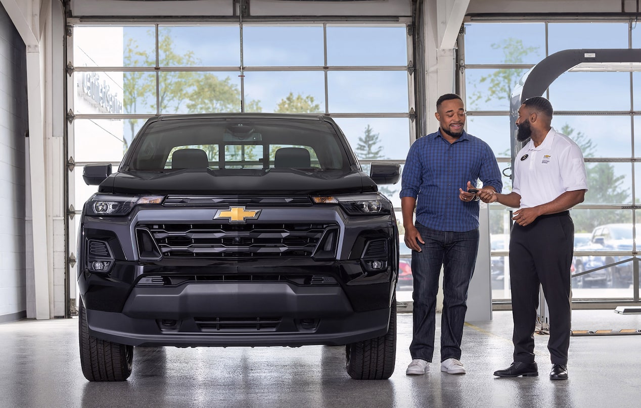 Deux personnes discutant près d’un véhicule Parcs GM.