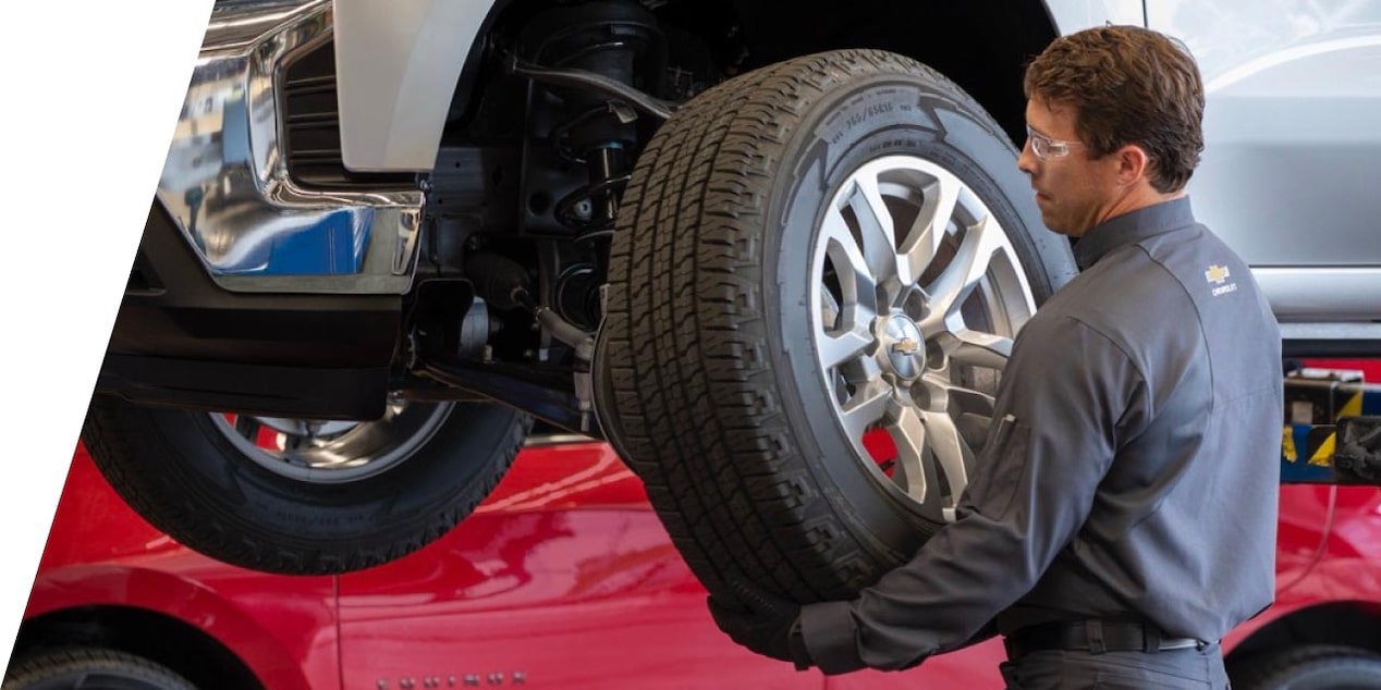 A car mechanic replacing a tire on a GM Fleet vehicle.