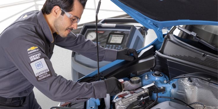 A Car Mechanic making fixes on the hood section of a GM Fleet vehicle.