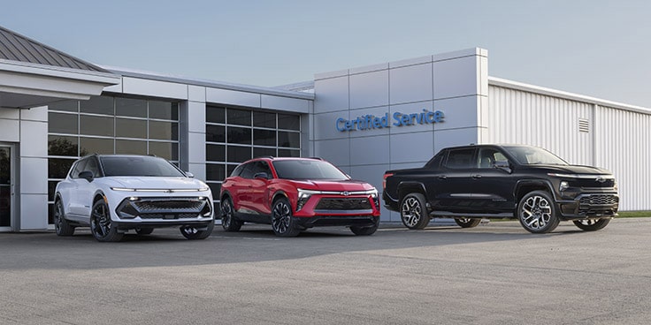 Trois véhicules commerciaux de GM stationnés à l'extérieur d'un bâtiment.