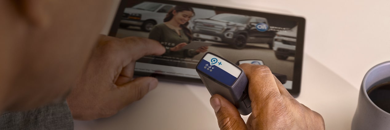 Une personne utilise une tablette tout en tenant l’adaptateur parc OnStar dans sa main droite.