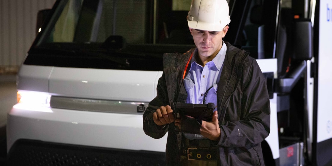 A construction worker using a tablet device near a Parcs GM vehicle.