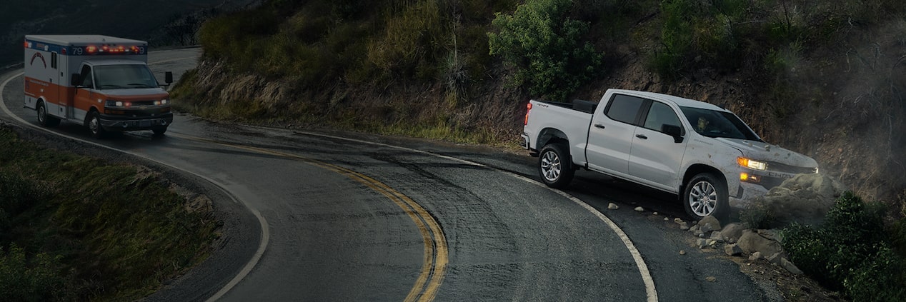 Un véhicule d’urgence s’approche d’un camion de flotte GM Fleet qui s’est écrasé dans un fossé.