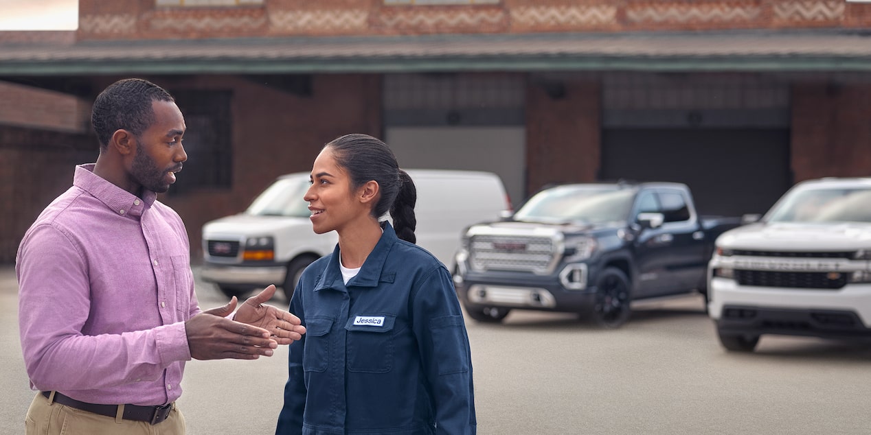 Deux personnes discutant près de trois camions Parcs GM.
